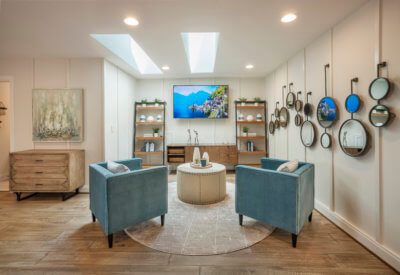 Loft of The Jefferson Model With a wall of Mirrors a TV and Two Blue chairs