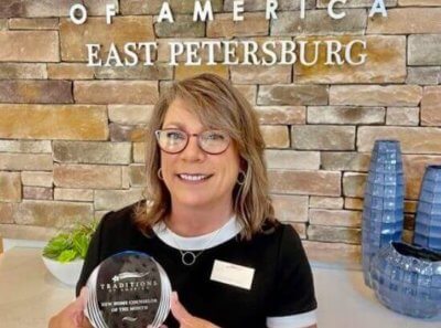 Staff member posing with an award in the east petersburg clubhouse