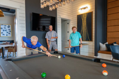 3 men playing pool in the traditions of America community clubhouse