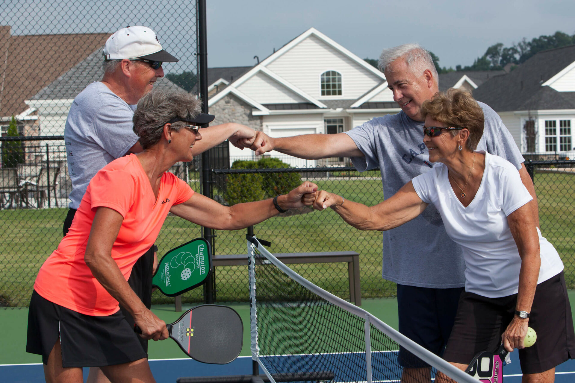 Active adult couples shaking hands over a pickle ball net