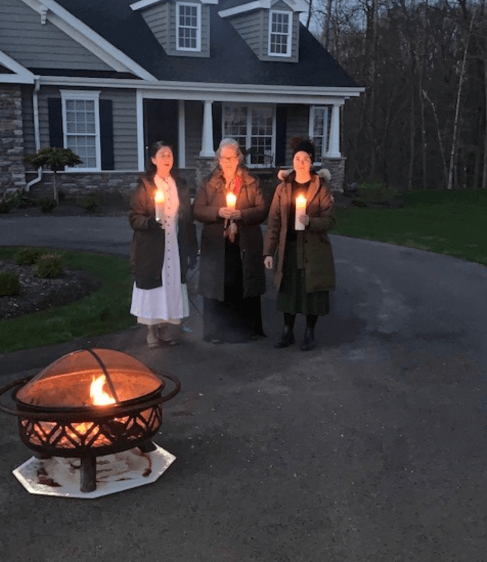 Three women holding candles in their driveway
