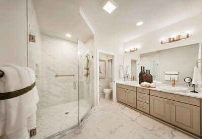 En suite bathroom with marble floors and glass doored shower in the Hancock model