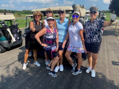 Group of Women in golf attire Posing in front of golf carts