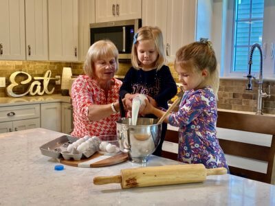 Grandma and Grand daughters baking together pouring milk into a mixing bowl