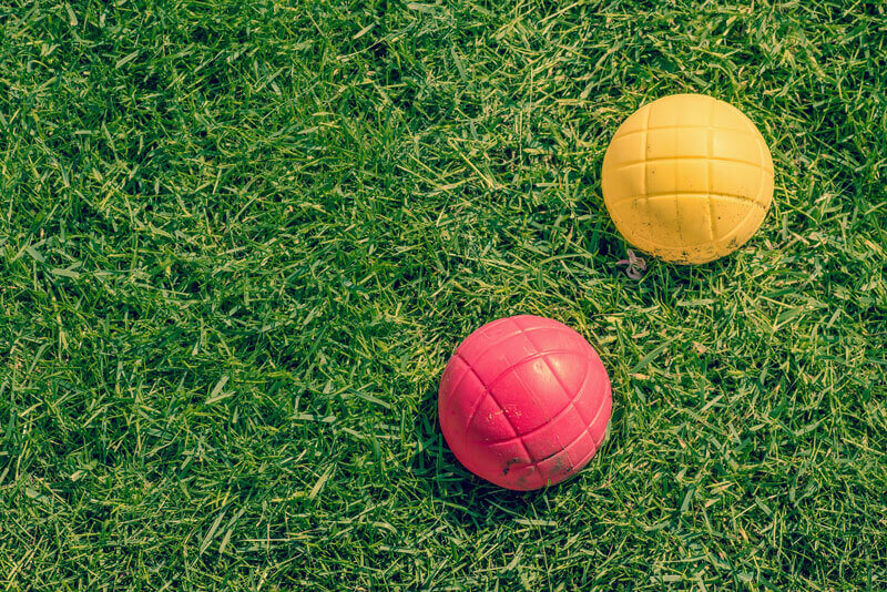 red and a yellow bocci ball on green grass