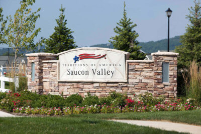 Traditions of America Saucon Valley Sign with Flowers in front