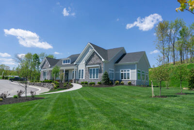 Large House with Grey siding and Stone accents with a large landscaped yard