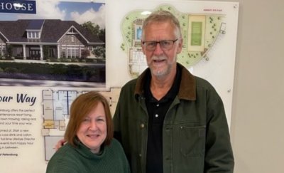 Two people Posing and smiling in front of Floor Plans