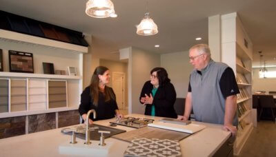Three People Standing around a Model Kitchen Island Customizing their Home