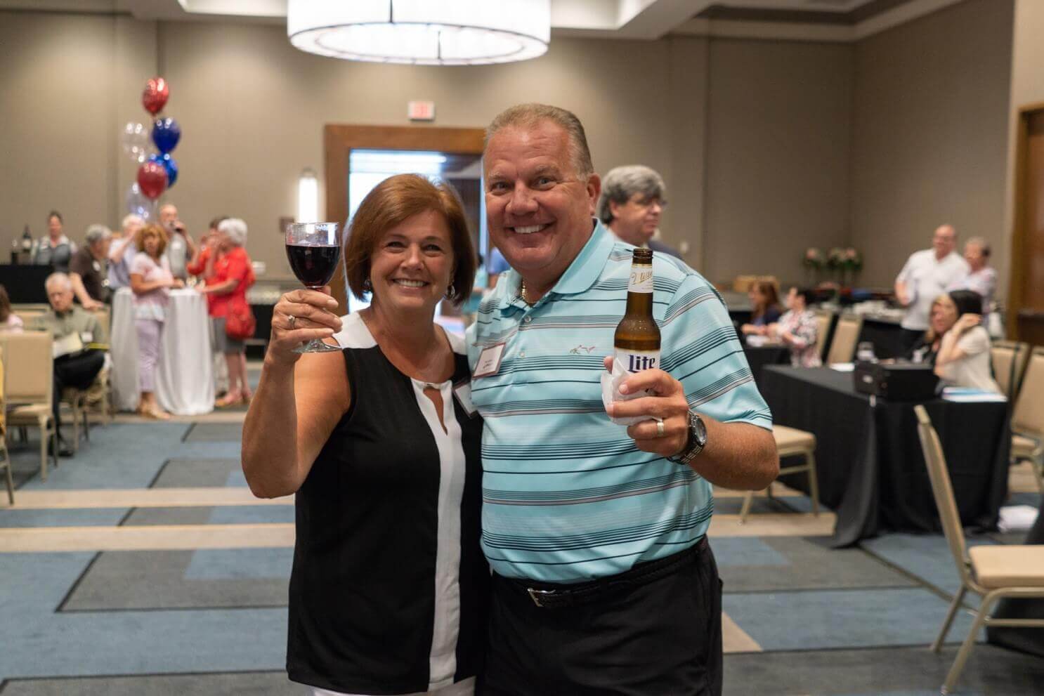 Two people posing for a photo and holding their drinks at a Traditions of America event