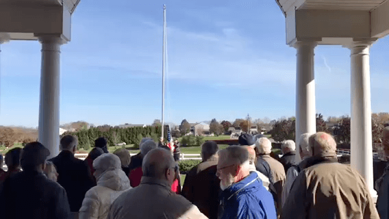 People standing outside while raising the flag