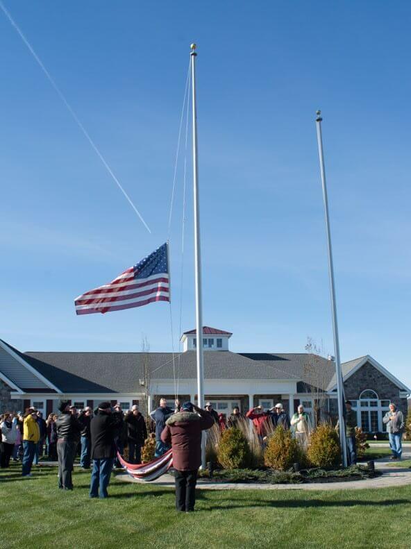people standing outside while raising the flag