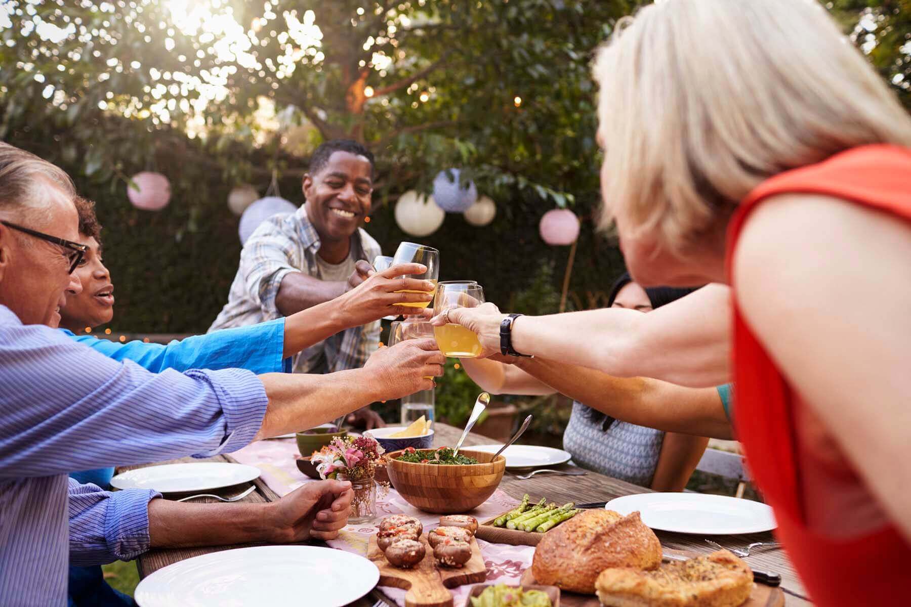 Group Of Mature Friends Enjoying Outdoor Meal In Backyard