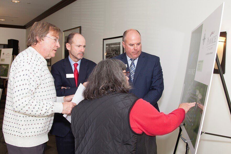 Four people looking at a board for the Pinnacle community from Traditions fo America