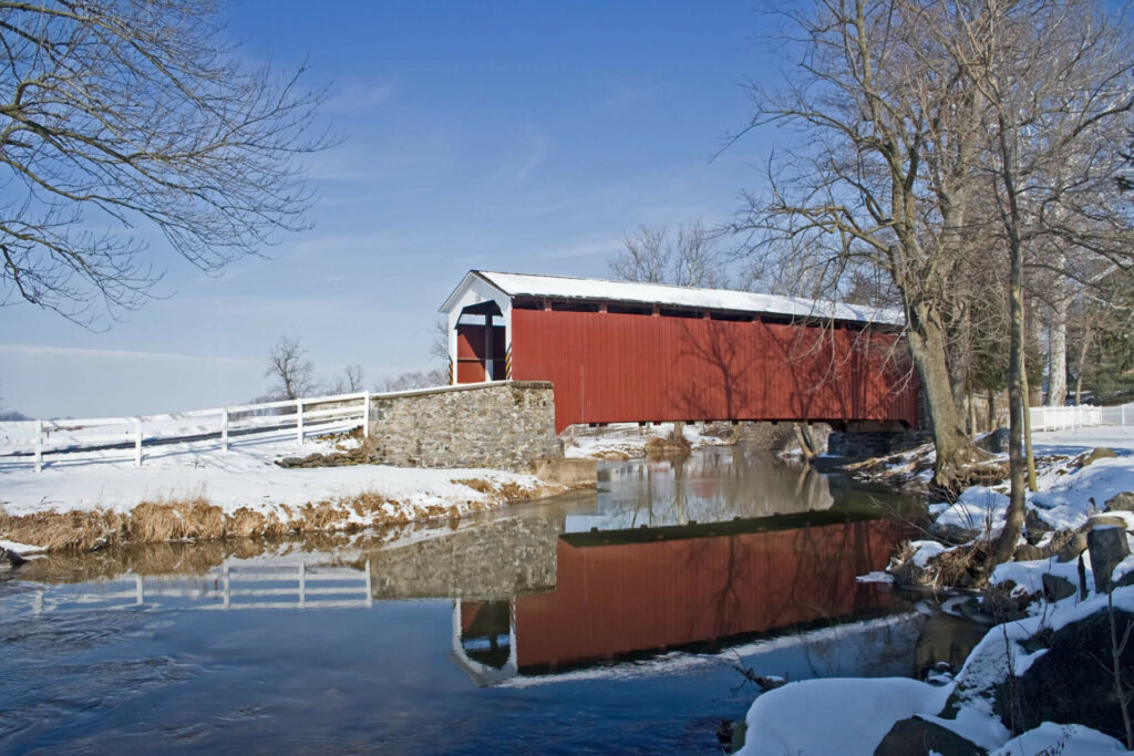 covered bridge going over a frozen pond in winter