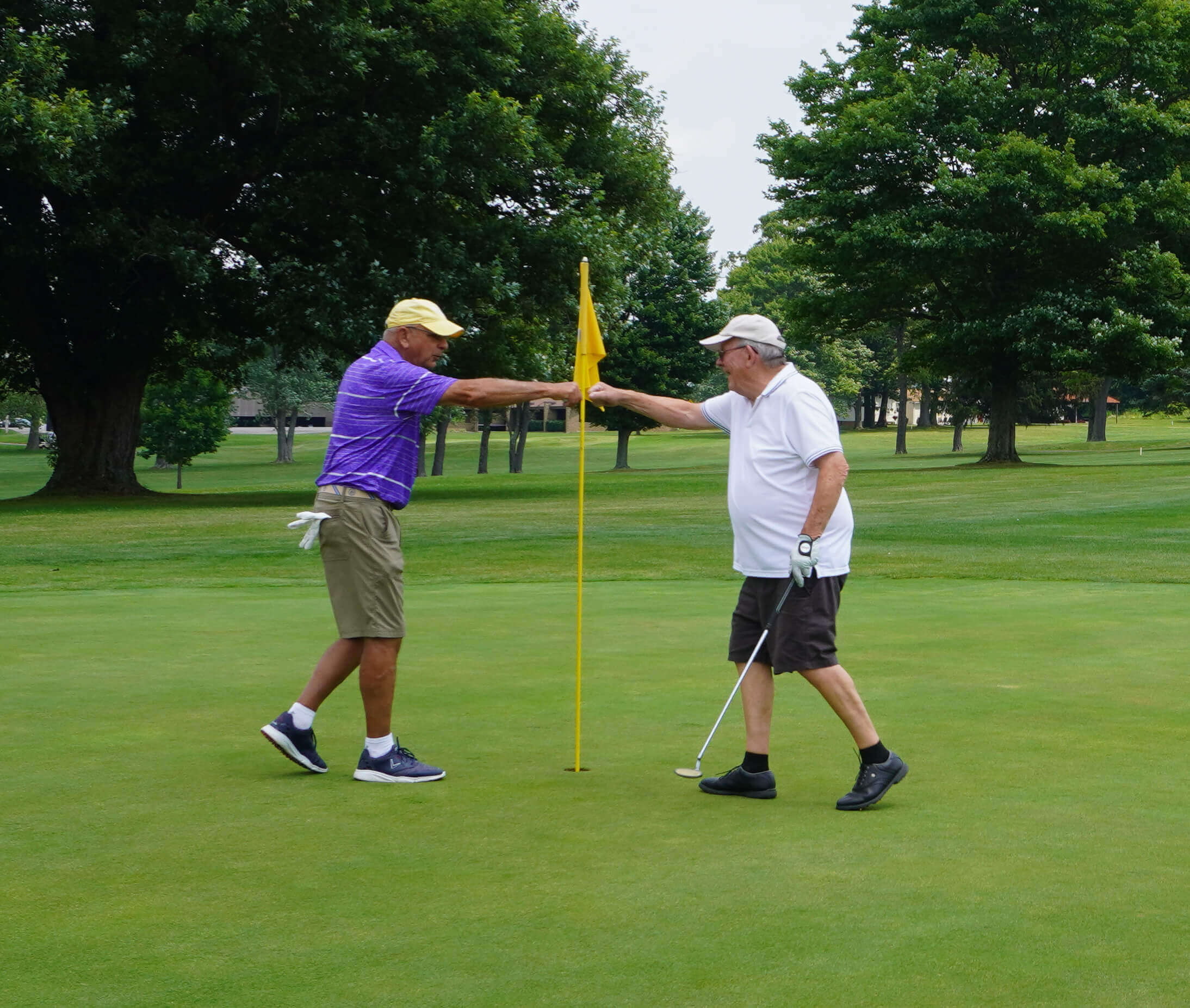 Two men shaking hands on the green of a golf course