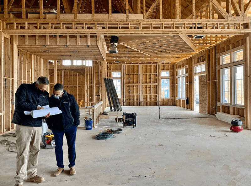 Two people standing in an under-construction home